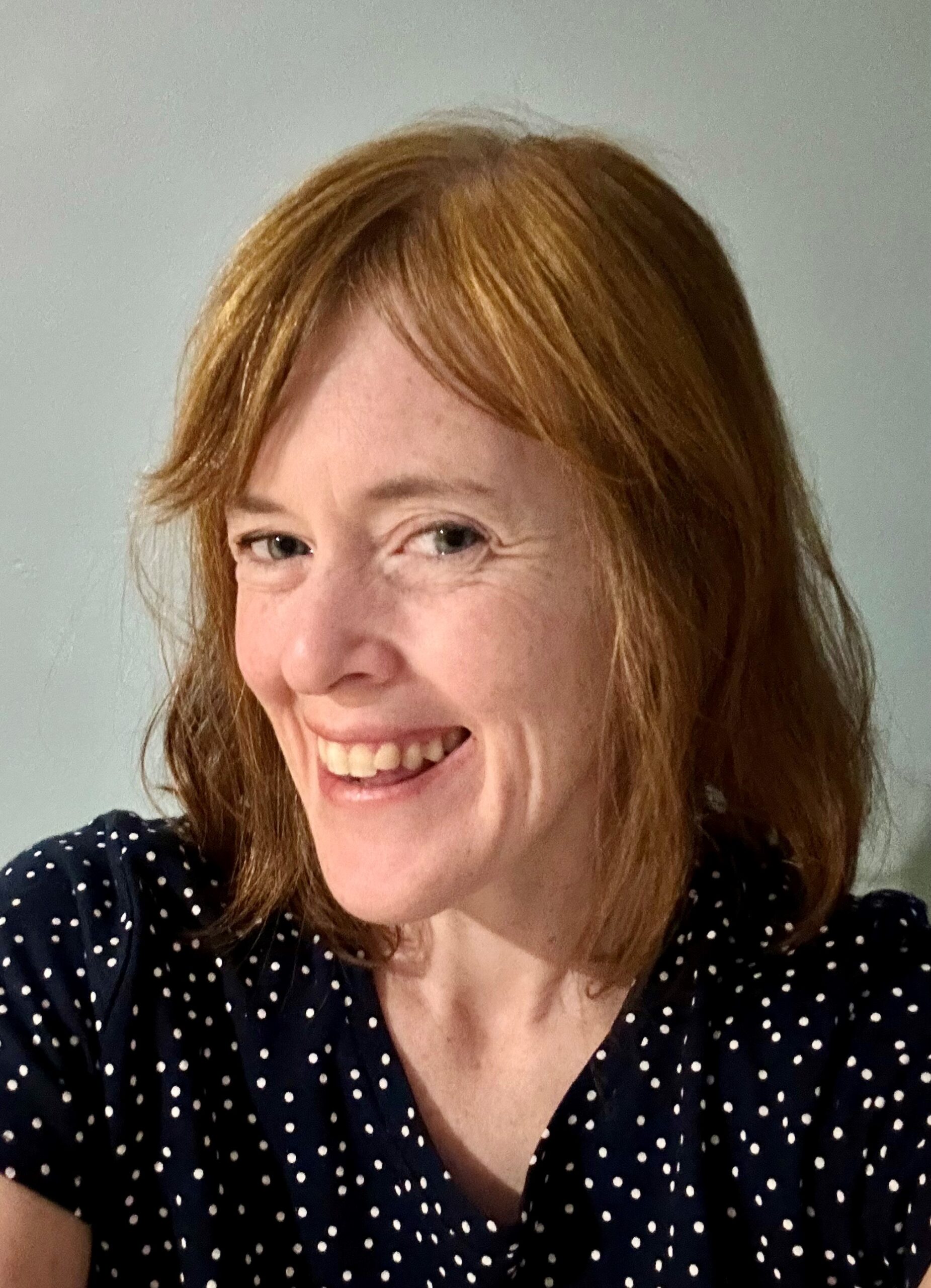 Jessica Steinhoff Engle has light reddish-brown hair and is wearing a black shirt with yellow polka dots